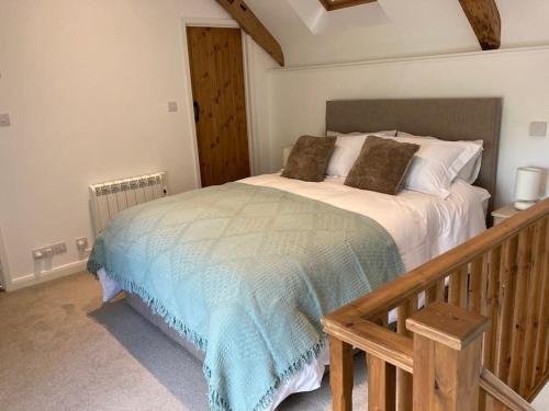 The Barn at Tanlake في Buckland St Mary: غرفة نوم مع سرير وبطانية زرقاء