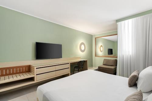 a bedroom with a bed and a flat screen tv at Sport Club by Isrotel Collection in Eilat