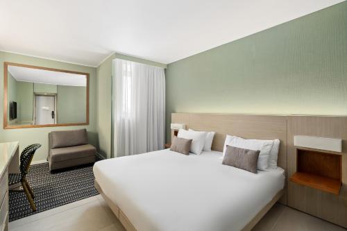 a hotel room with a large bed and a chair at Sport Club by Isrotel Collection in Eilat