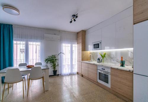 een keuken met witte kasten en een tafel en stoelen bij NEW Beach Apartments in Alicante