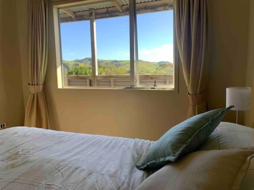 um quarto com uma cama e uma janela com vista em Awhitu Sunset Paradise em Awhitu