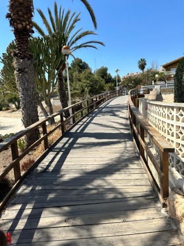 un ponte di legno su una spiaggia con una palma di Relax Casa Costa Blanka a Santa Pola