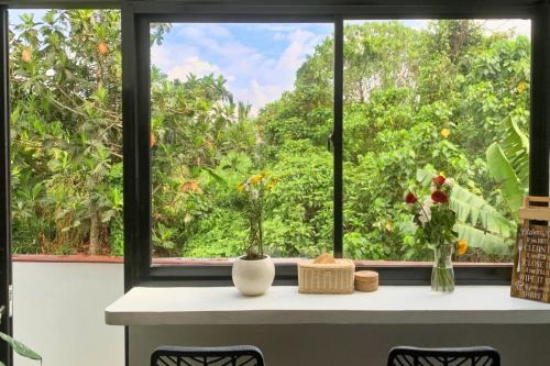 a window with vases and flowers on a table at UNIQUE HOUSE UMA DESA in Kesiman