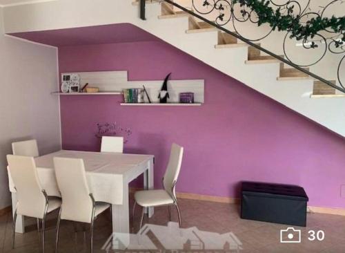 une salle à manger avec des murs violets, une table et des chaises dans l'établissement Villa Anzio, à Anzio
