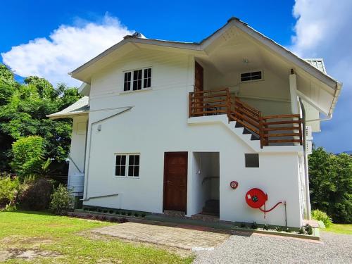 a white house with a staircase on it at Rêve Tropical Chambres D'hôtes in Anse a La Mouche