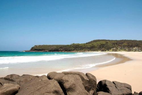 a beach with rocks in front of the ocean at Merry Beach Getaway in Kioloa
