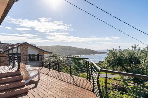 a deck with a bench and stairs next to the ocean at Merry Beach Getaway in Kioloa