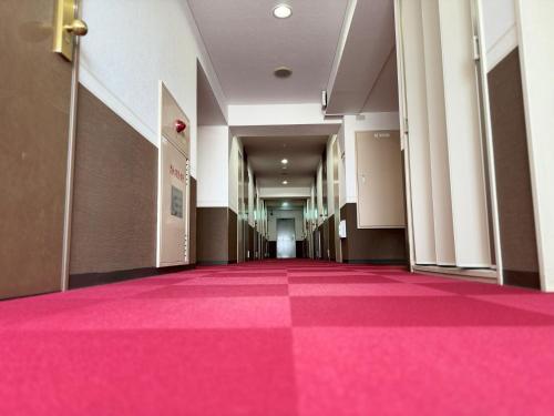 a hallway with a pink carpeted floor in a building at Hotel Alpha Inn Akita in Akita