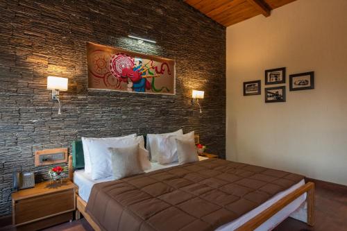 a bedroom with a large bed and a brick wall at Rudraa resort and restaurant in Hawālbāgh