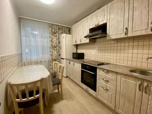 uma cozinha com uma mesa, um frigorífico e um lavatório em UKA Comfort, 3х комнатная в центре. em Öskemen