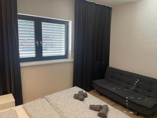 a bedroom with a bed and a couch and a window at City Apartment - Michalovce in Michalovce