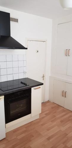 - une cuisine blanche avec un poêle noir four supérieur dans l'établissement Appartement 2 pièces 20 m2 gare Trouville, à Trouville-sur-Mer