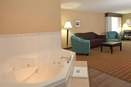 Habitación de hotel con bañera y sala de estar. en Holiday Inn Express Hotel & Suites Vernon, an IHG Hotel, en Vernon