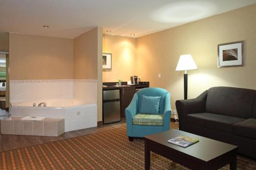 a living room with a couch and a chair and a tub at Holiday Inn Express Hotel & Suites Vernon by IHG in Vernon
