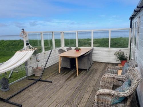 d'un balcon avec une table et des chaises donnant sur l'océan. dans l'établissement Traumblick, Traumlage Nr 31 erste Reihe direkt am Wattenmeer, à Westerland