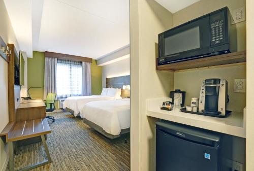a hotel room with a bed and a flat screen tv at Holiday Inn Express Whitby Oshawa, an IHG Hotel in Whitby
