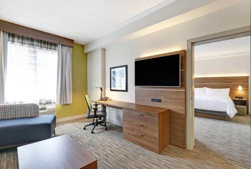 a hotel room with a bed and a desk with a television at Holiday Inn Express Whitby Oshawa by IHG in Whitby