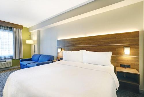 a hotel room with a large bed and a blue chair at Holiday Inn Express Whitby Oshawa by IHG in Whitby