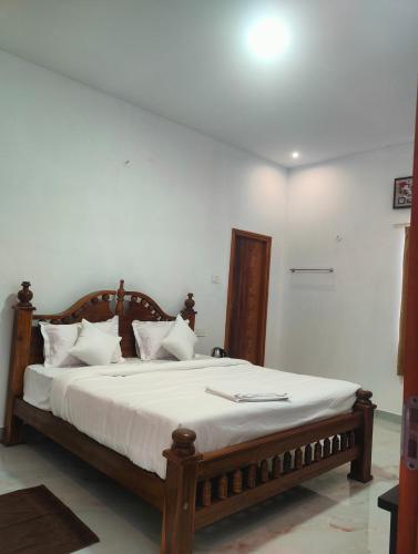 a bedroom with a large bed with white sheets at REGALIA ROOMS KODAI in Kodaikānāl
