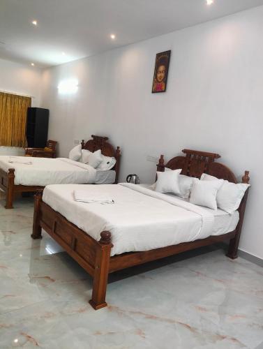 two beds in a room with white walls at REGALIA ROOMS KODAI in Kodaikānāl