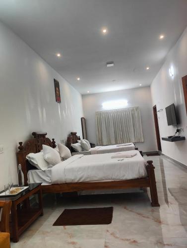 a bedroom with a large bed with white sheets and pillows at REGALIA ROOMS KODAI in Kodaikānāl