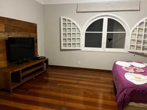 uma sala de estar com uma televisão de ecrã plano e 2 janelas em Quarto super luxo Alphaville em Barueri