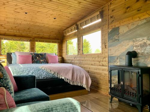 a log cabin bedroom with a bed and a fireplace at The Showman, Luxury Camper in Halford