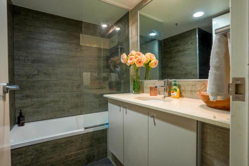 baño con lavabo y jarrón de flores en CBD Central - 1BDR Apt - Sleeps 6 - Sebel 4 Star Resort en Brisbane
