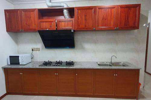 een keuken met houten kasten, een fornuis en een wastafel bij Exquisite 3-Bedroom Unit With Free Parking. in Nadi