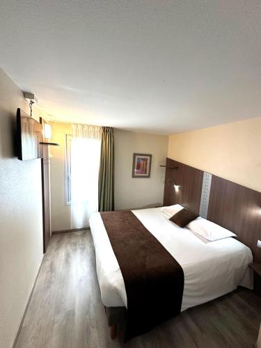 a hotel room with a large bed and a window at Fasthotel Toulouse Blagnac Aéroport in Blagnac
