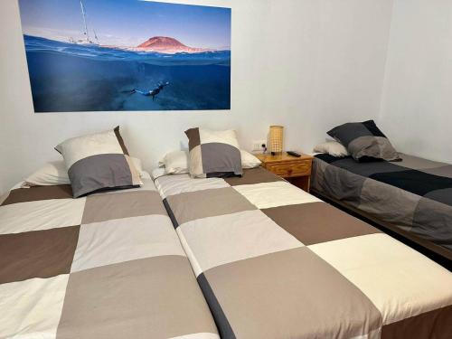 a bedroom with two beds and a painting on the wall at La Graciosita Traditional Home in Caleta de Sebo