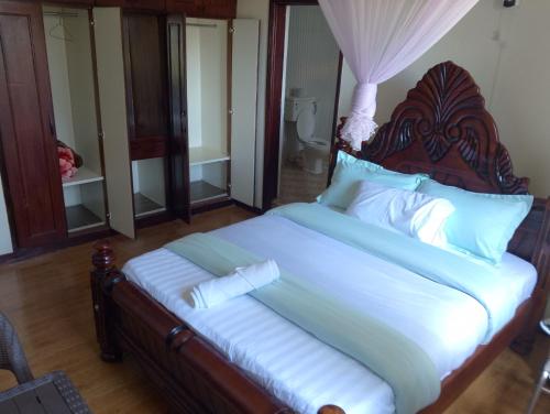 a bedroom with a large bed with a wooden headboard at DISCOVERY COURTS HOTEL in Entebbe