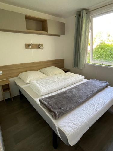 un grand lit dans une chambre avec une fenêtre dans l'établissement Joli Mobil home Camping 4 Le Bois Masson A34, à Saint-Jean-de-Monts