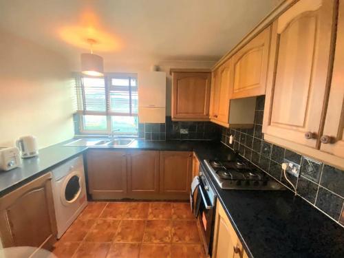 a kitchen with wooden cabinets and a stove top oven at Gravesend 1 bedroom Apartment in Kent