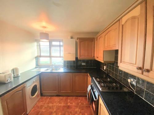a kitchen with wooden cabinets and a stove top oven at Gravesend 1 bedroom Apartment in Kent
