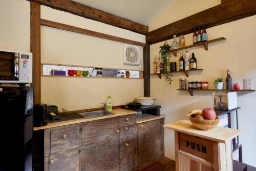 una cocina con fregadero y una barra con un tazón de manzanas en ゲストハウス　グランフォティア, en Yamagata