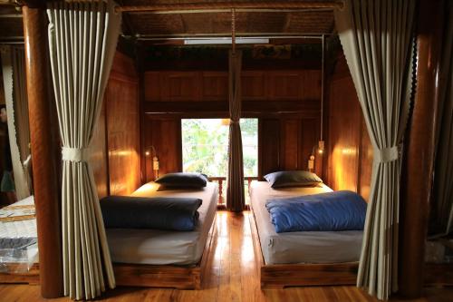Duas camas num quarto com cortinas num quarto em Ha Giang Eco Stone House - Tours & Rental Motorbike em Bản Kin