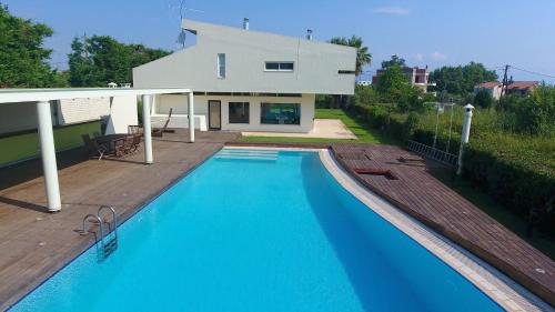 a villa with a swimming pool in front of a house at Villa Temptation in Kamena Vourla