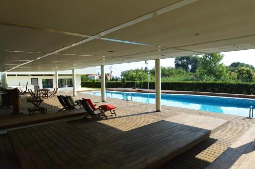 a covered deck with chairs and a swimming pool at Villa Temptation in Kamena Vourla