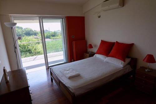 a bedroom with a bed with red pillows and a window at Villa Temptation in Kamena Vourla