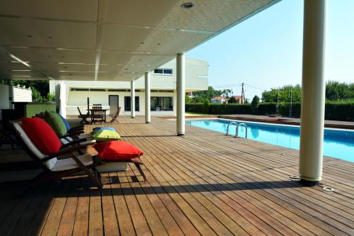 a wooden deck with chairs and a swimming pool at Villa Temptation in Kamena Vourla
