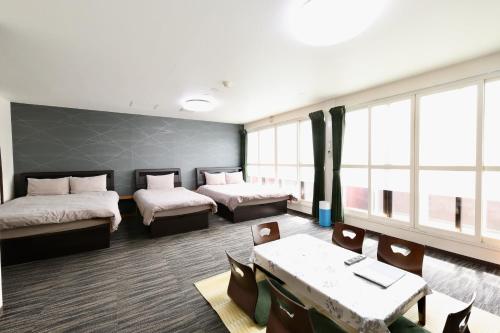 a room with two beds and a table and chairs at Apartment Susukino Hakuhou Building in Sapporo