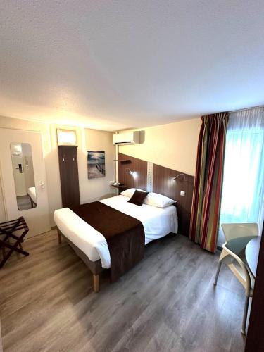 a hotel room with a large bed and a chair at Fasthotel Toulouse Blagnac Aéroport in Blagnac