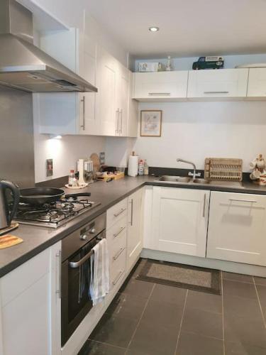 a kitchen with white cabinets and a stove top oven at 3 Bedroom Home Near Windsor Castle, Legoland, & Heathrow in Slough