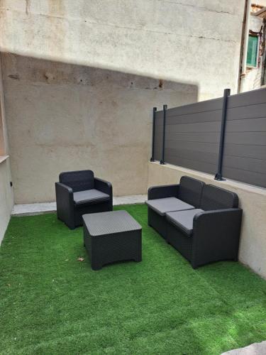 deux chaises noires et des chaises longues sur une terrasse avec de l'herbe dans l'établissement Appartement 3 pièces à 5 minutes de la plage N7, à Saint-Laurent-du-Var
