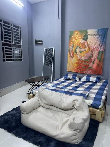 1 dormitorio con 1 cama blanca y una pintura en la pared en Nhà Nghỉ Thành Đạt, en Can Tho