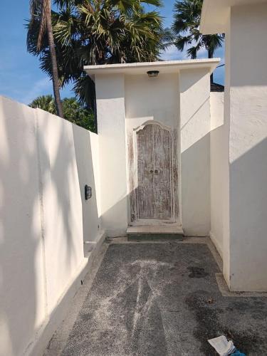 a white building with a door with a palm tree at Hasta La Vista Villa Amed in Amed
