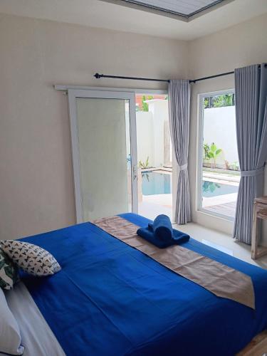 een slaapkamer met een blauw bed en een groot raam bij Hasta La Vista Villa Amed in Amed