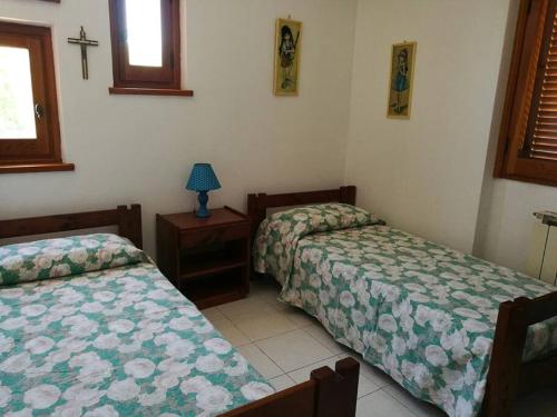 um quarto com duas camas e uma cruz na parede em Villa c/Piscina 100mt dal mare Roma G em Marina di San Nicola