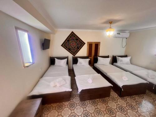 um quarto com três camas e uma janela em Native Teracce em Bukhara